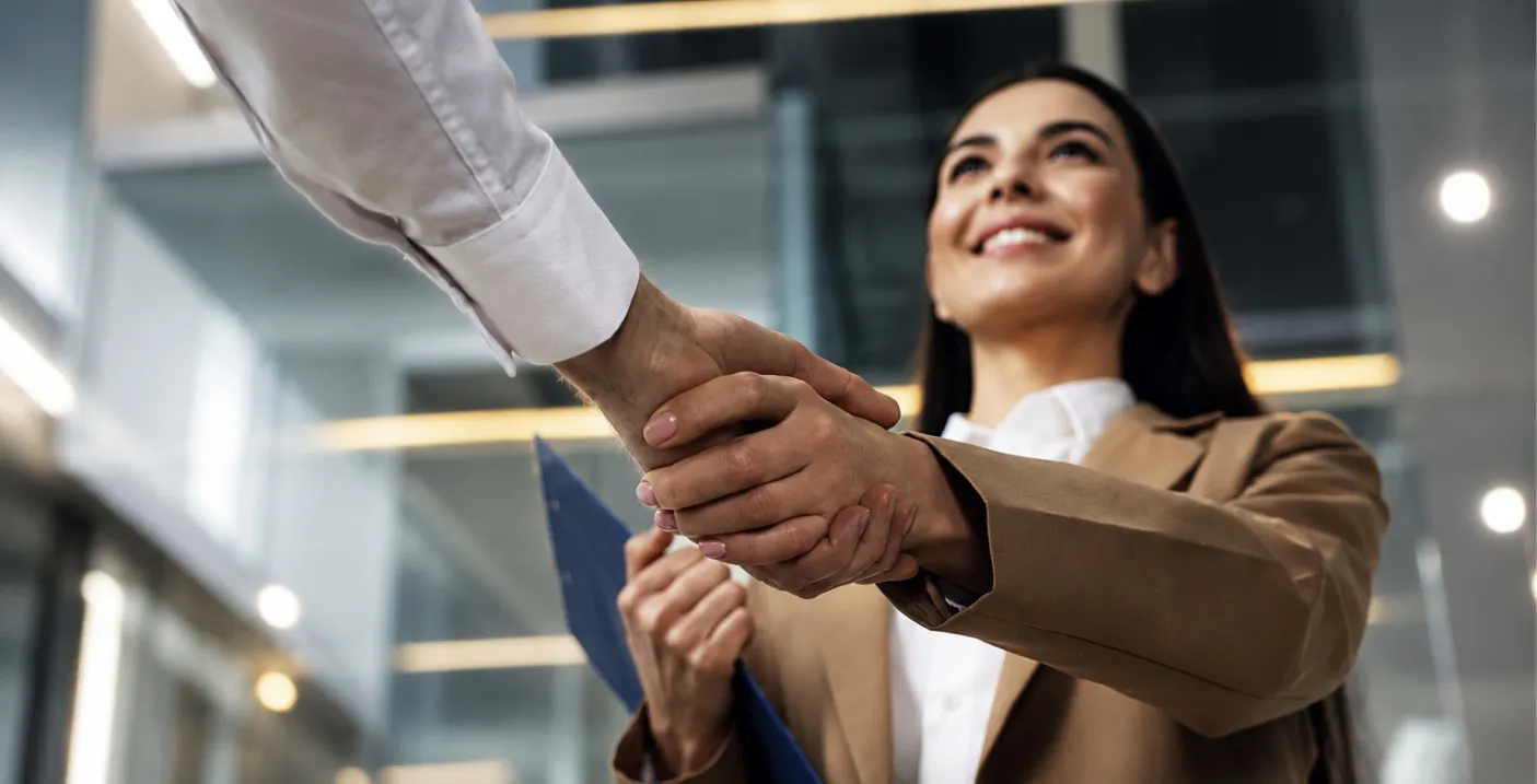 Profesional estrecha la mano de una candidata durante una entrevista de trabajo, reflejando cómo el liderazgo organizacional fortalece la gestión del talento humano, la selección de personal y la construcción de equipos de alto desempeño.