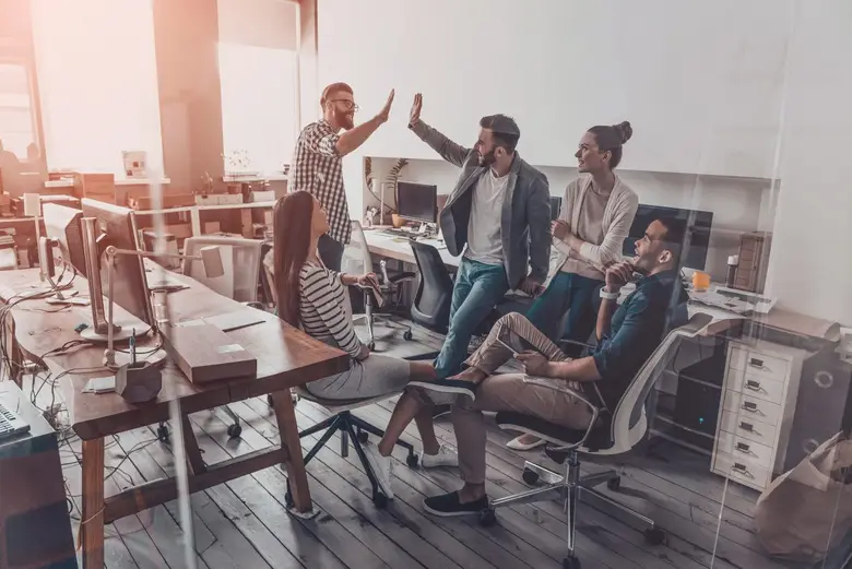 Equipo de trabajo diverso sonriendo y compartiendo en un ambiente positivo, reflejando los beneficios del bienestar laboral y la importancia del bienestar emocional en el entorno profesional. 