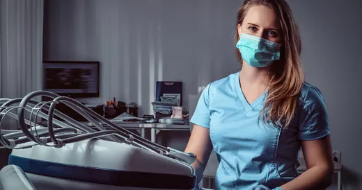 Una mujer en uniforme azul sentada en una silla dental