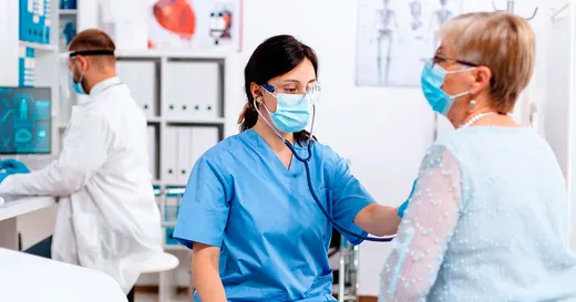 Una mujer en bata de hospital revisa a otra mujer.