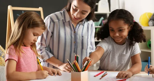 Una maestra ayudando a niñas con sus tareas escolares.