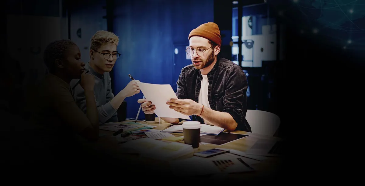 Un grupo de personas sentadas alrededor de una mesa con laptops.