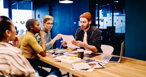 Un grupo de personas sentadas alrededor de una mesa con laptops.