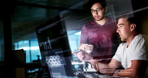 Dos hombres mirando gráficos en una pantalla de computadora.