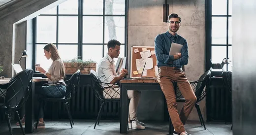 Joven profesional sostiene documentos mientras sonríe en la oficina