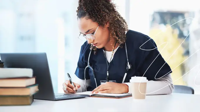 Un médico sonriente en su consultorio con sus colegas, tiene una laptop en el escritorio donde toma sus clases online.