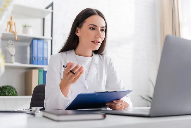 Psicóloga guiando una sesión de terapia emocional frente una computadora mientras está sentado en un sofá. 