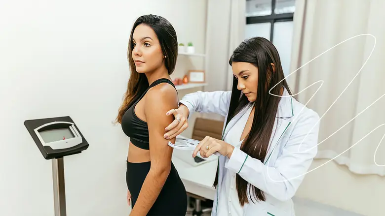 Una doctora escribiendo en un papel mientras está sentada en una mesa con frutas y verduras.